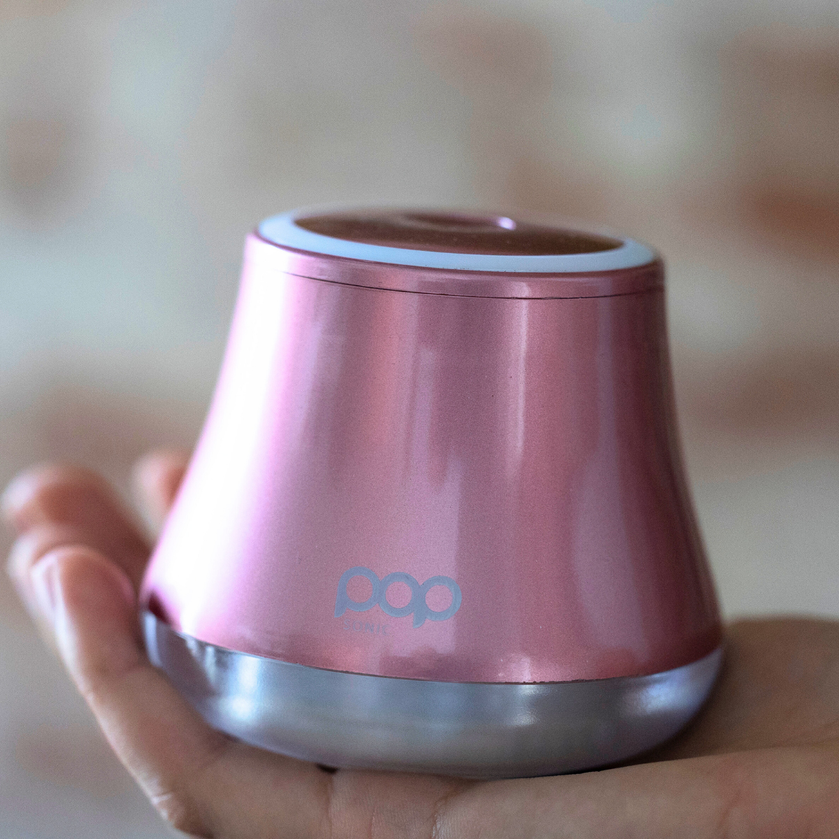 Pink Fabric Shaver held in a hand against a blurred background