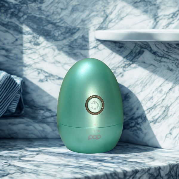 Lint colored egg-shaped product displaying a power button with a black and white granite background