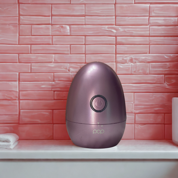 Lavender egg-shaped product on a white bathroom counter with pink tile in the background