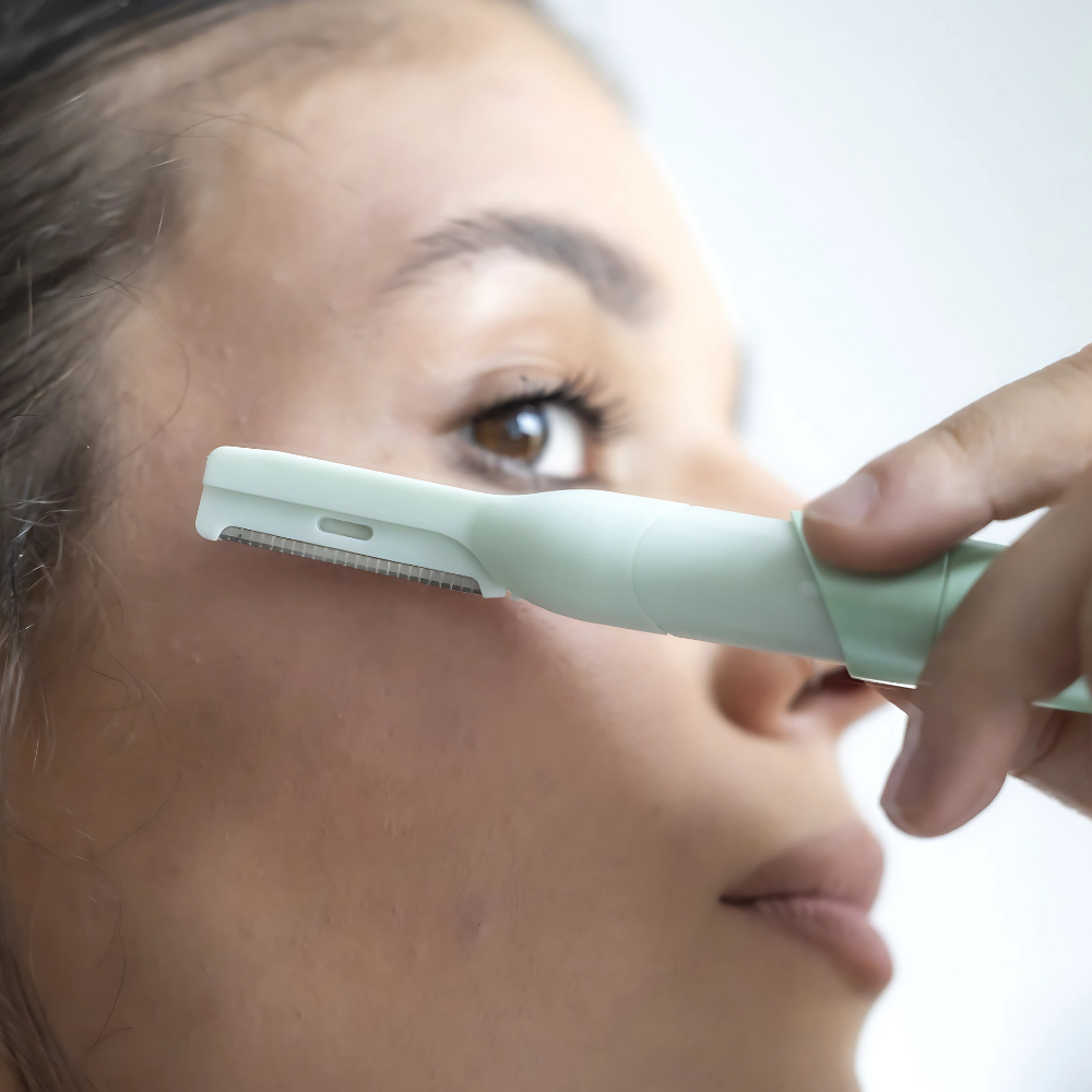 Woman using a green Hair Planer tool on her face.