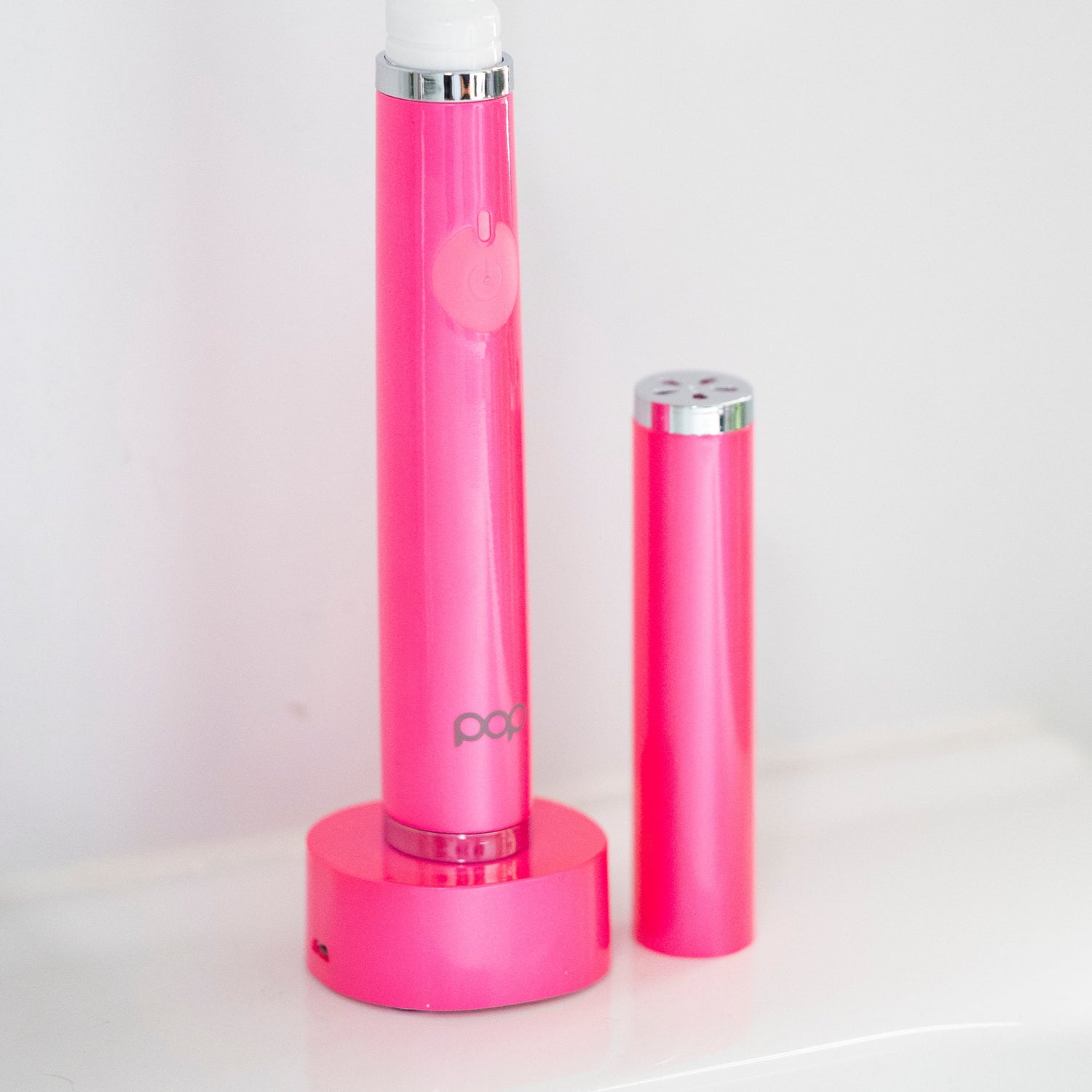 Pink electric toothbrush with a matching lid on a white background