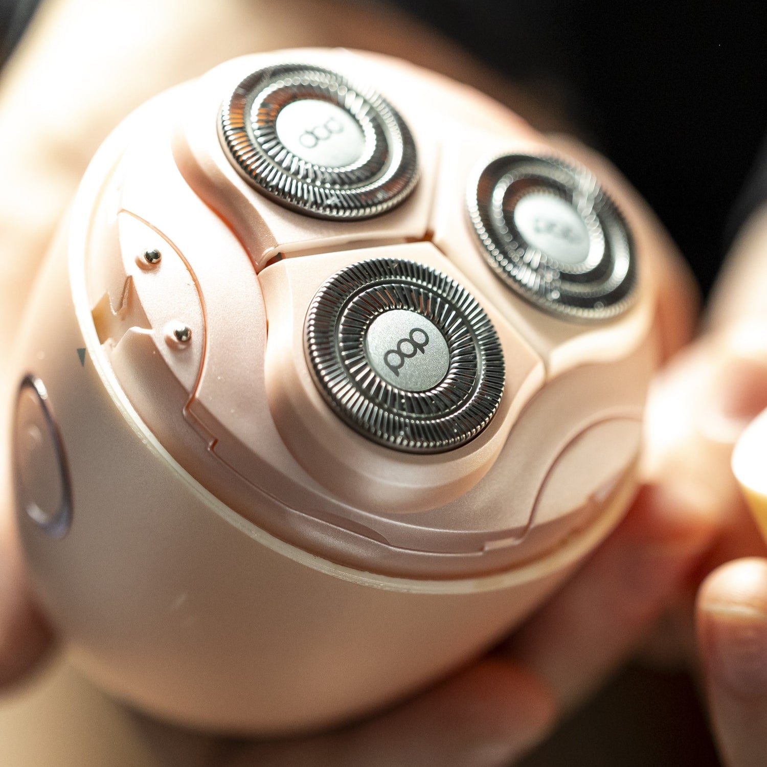Close-up of a person holding a pink electric shaver