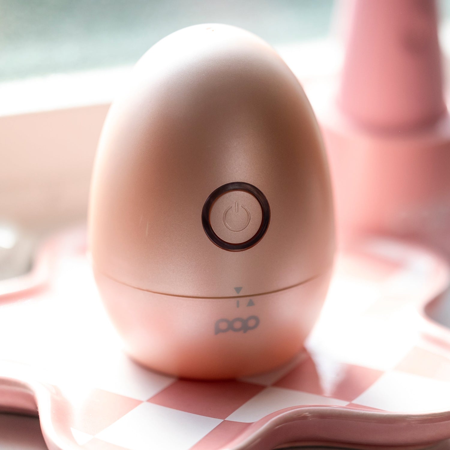 Pink electronic shaver with a power symbol on a pink checkered surface