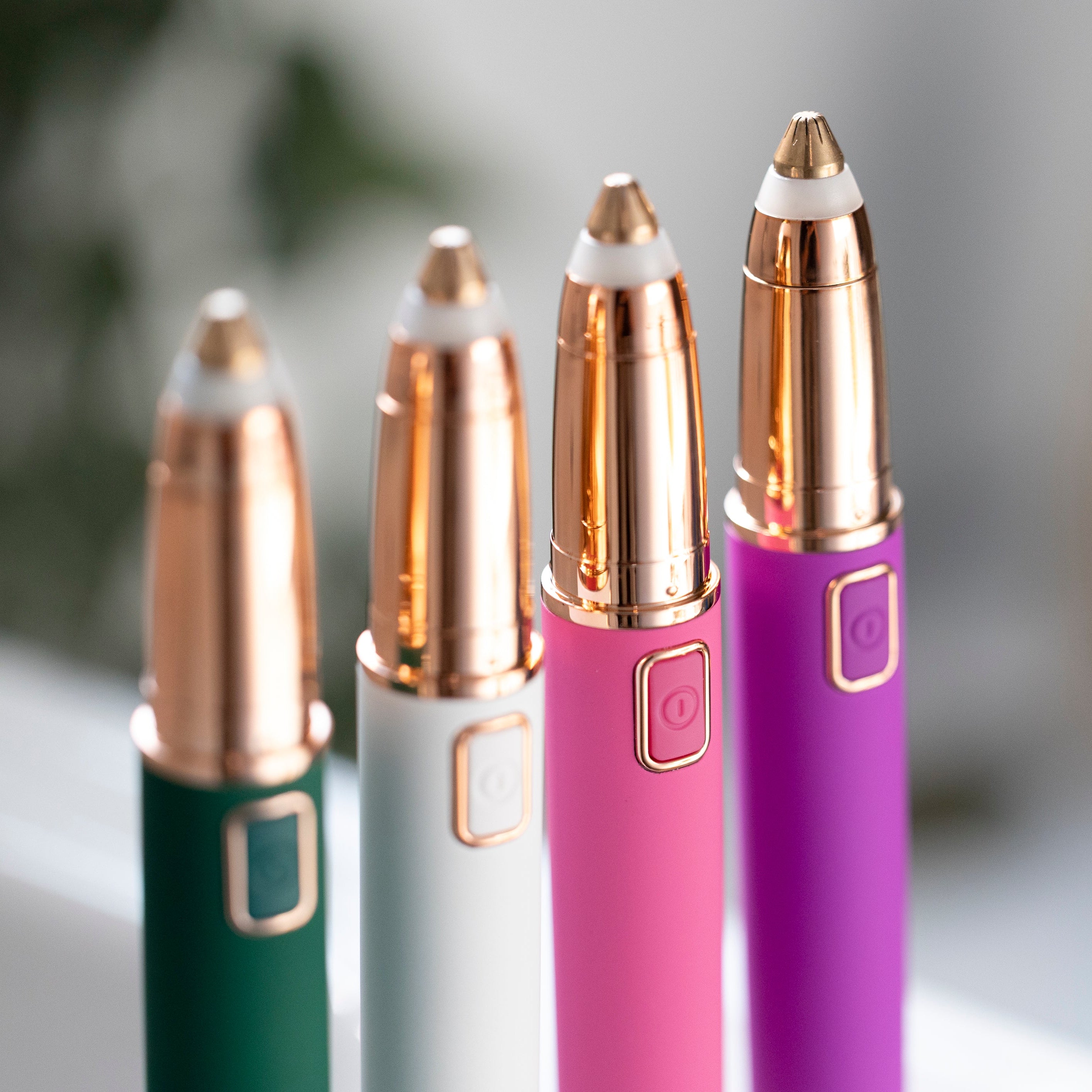 An image of all 4 eyebrow shapers in Green, White, Pink, and Purple, all facing forward so you can see the On/Off buttons.