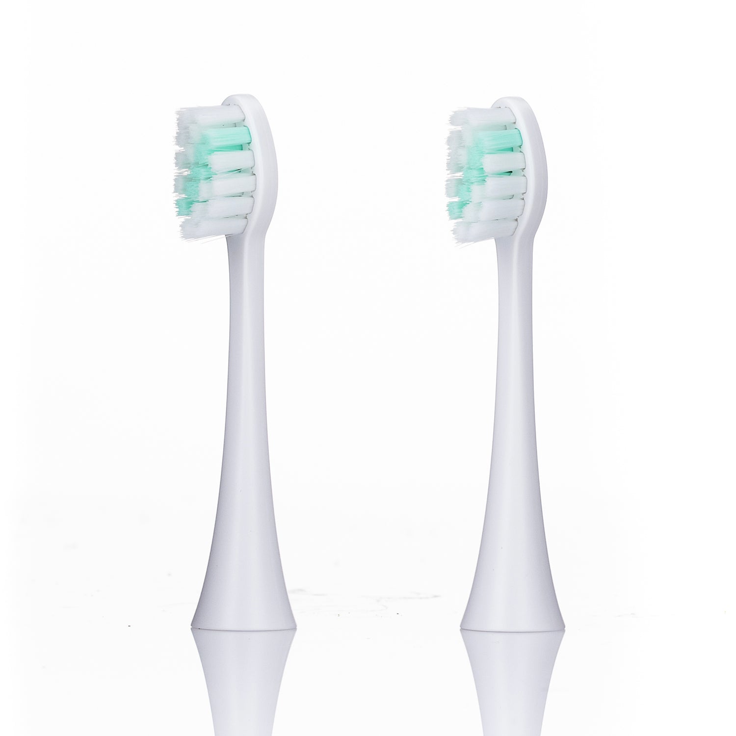 Two white electric toothbrush heads with green bristles on a white background