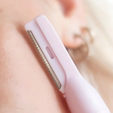 Woman using a pink hair planer device on her face