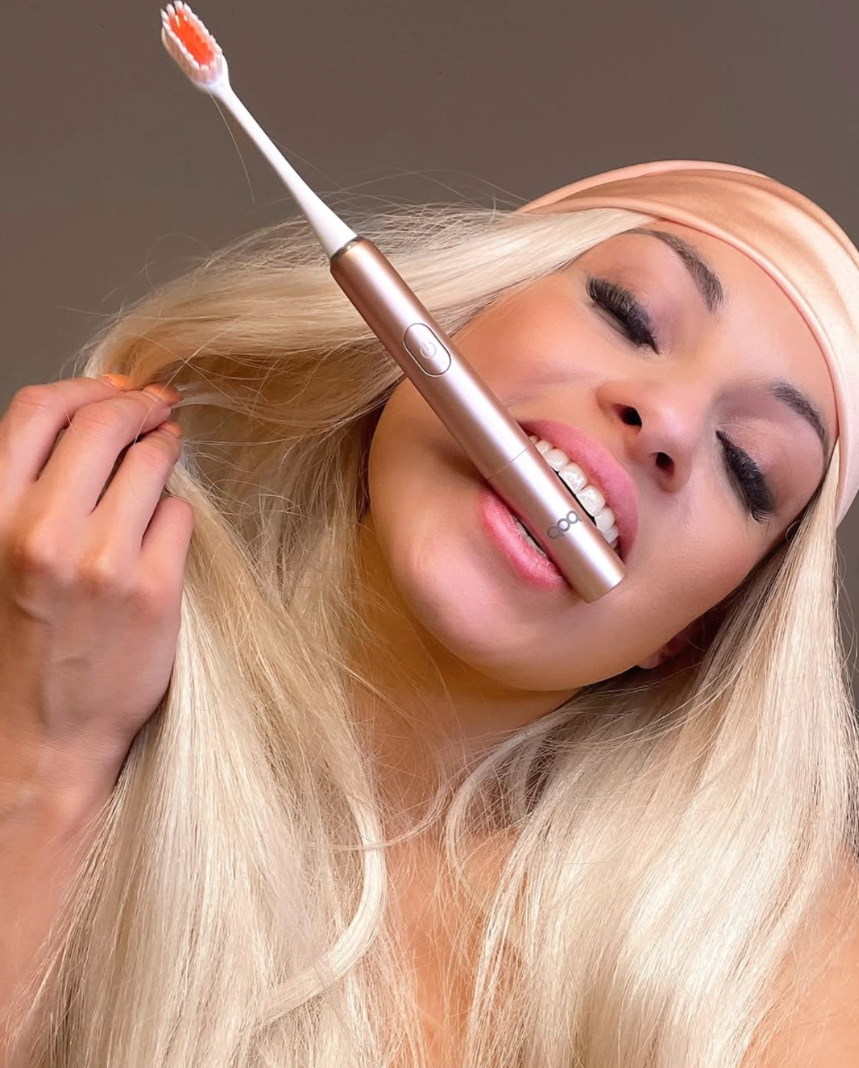 Girl with blonde hair with a rose golf toothbrush in between her teeth