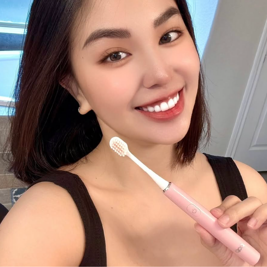 Woman holding a pink toothbrush with a neutral background