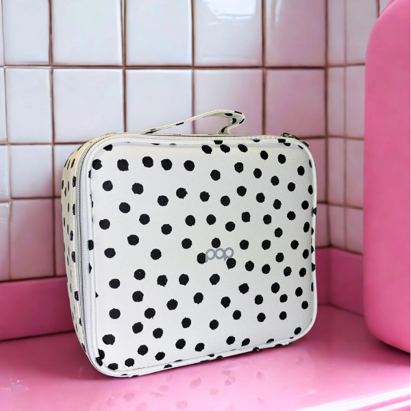 Makeup case in black and white polka dots on a pink bathroom counter with white tile