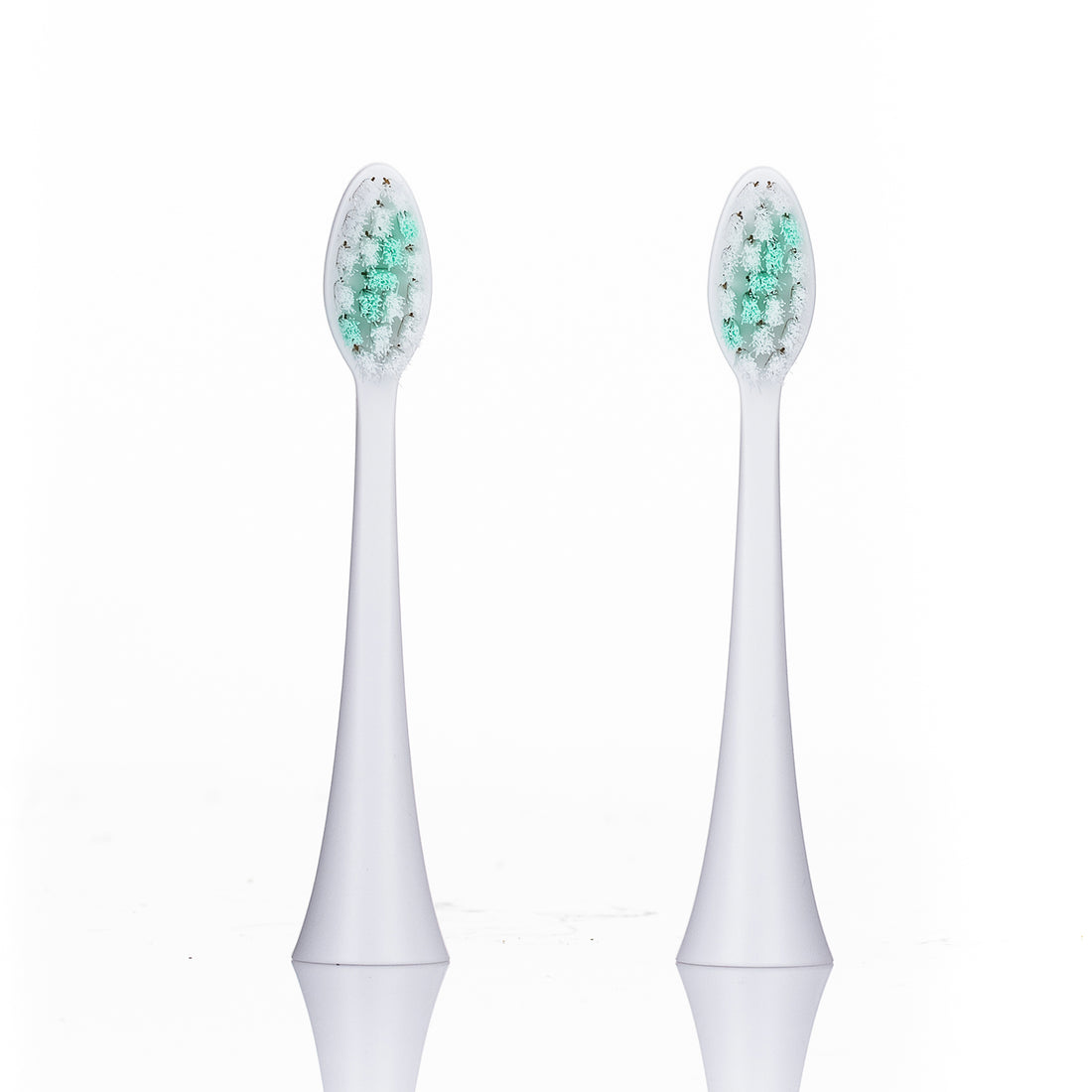Two white electric toothbrush heads with green bristles on a white background