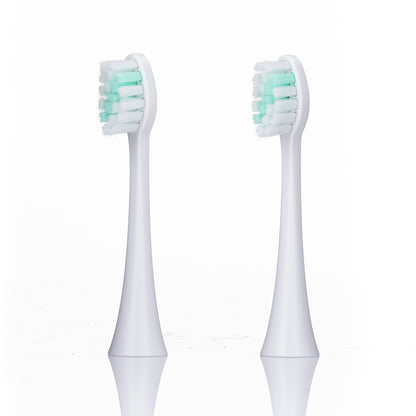 Two white electric toothbrush heads with green bristles on a white background